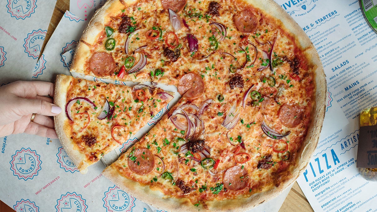 Picture of finished cooded Pizza with a hand taking a slice.