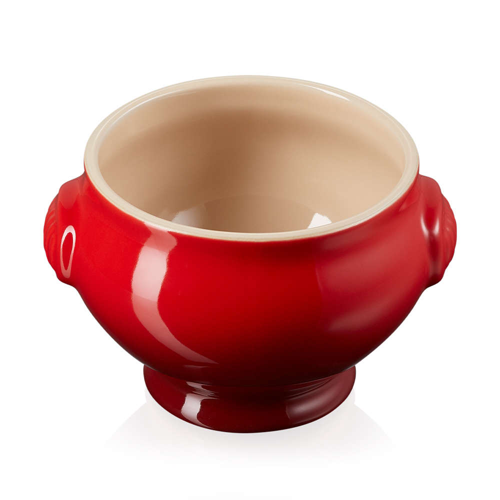 A red soup bowl with snall handles on each side that looks empty to the un trained eye